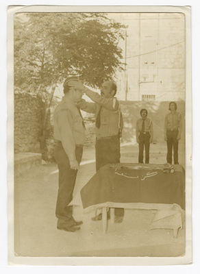 A Photograph of a Scout Member Placing a Cap atop the Head of Another Member