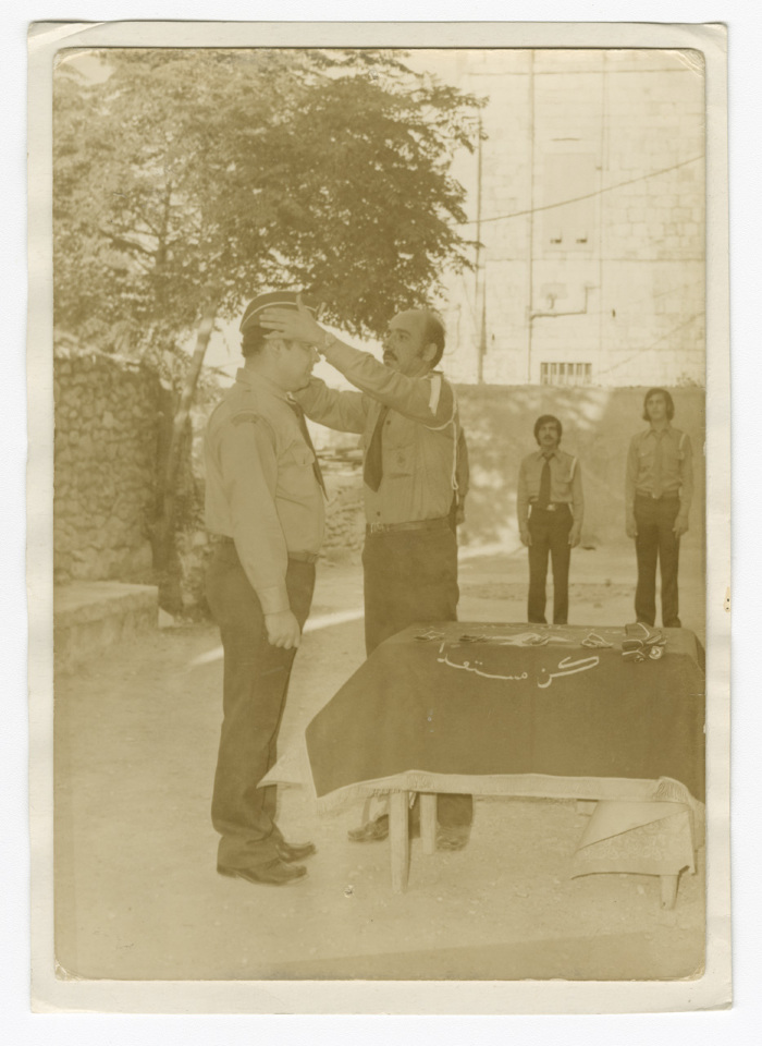 A Photograph of a Scout Member Placing a Cap atop the Head of Another Member
