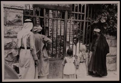 صورة لرجال وطفلين يقفون  أمام باب  إحدى المستشفيات، ثلاثينيات وعشرينيات القرن الماضي