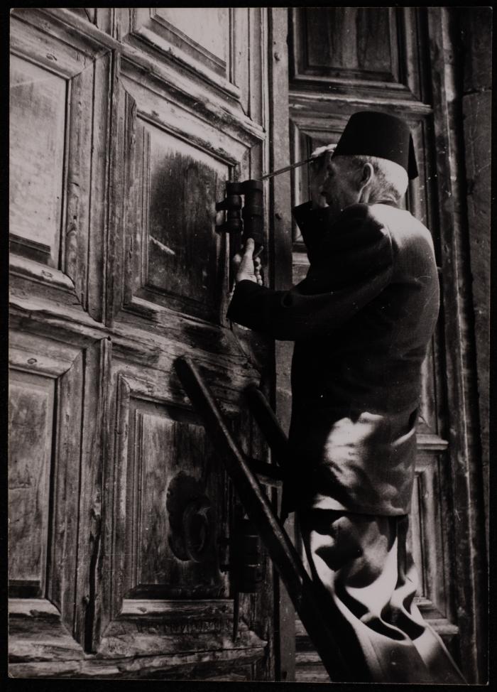 رجل يفتح باب كنيسة القيامة في القدس، تصوير حنا صافية، خمسينيات القرن العشرين