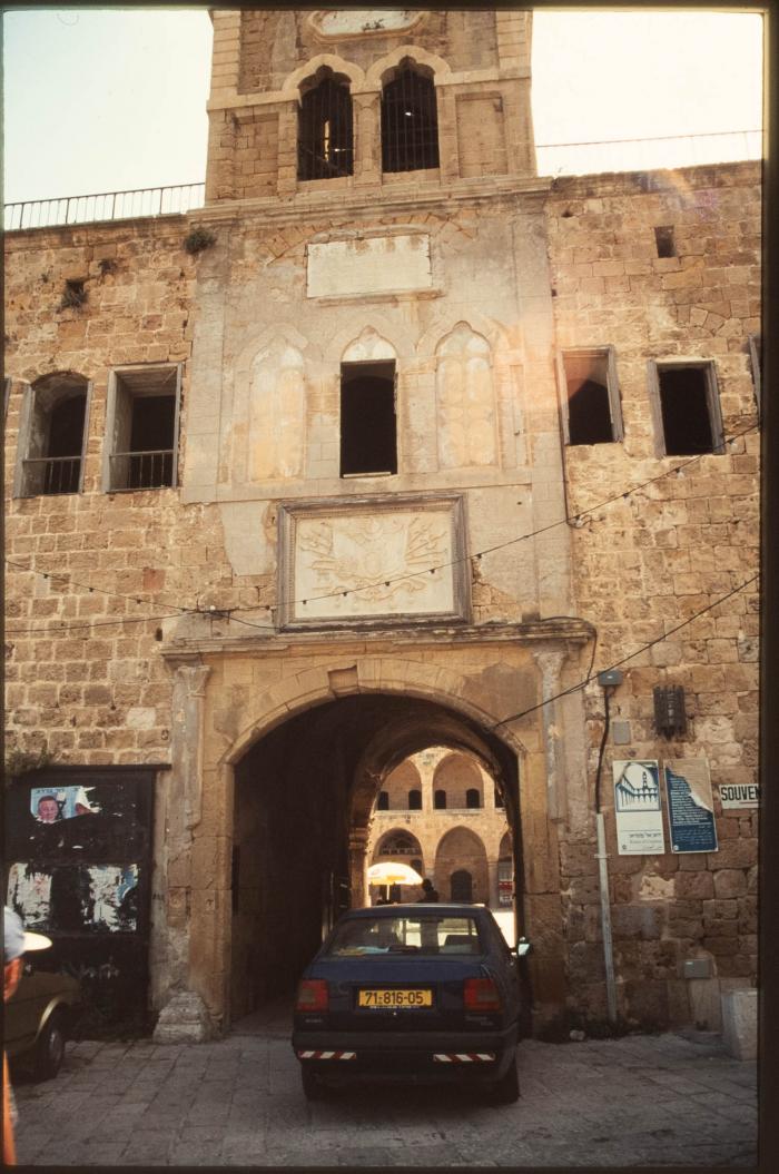 صورة لبرج الساعة في أعلى المدخل الشمالي لخان العمدان في مدينة عكا المحتلة في التسعينيات