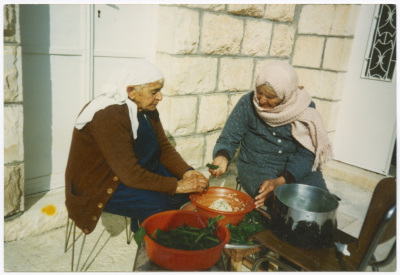Two women cooking cauliflower leaves