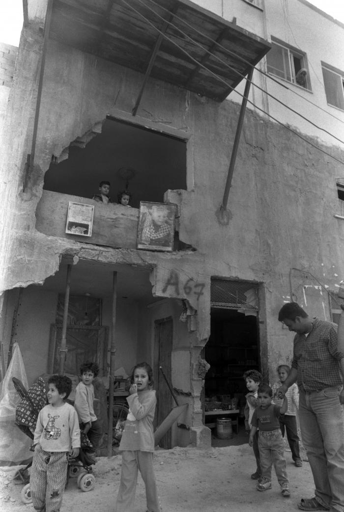 عائلة فلسطينية أمام منزلهم المتضرر، مخيم جنين، حزيران 2002