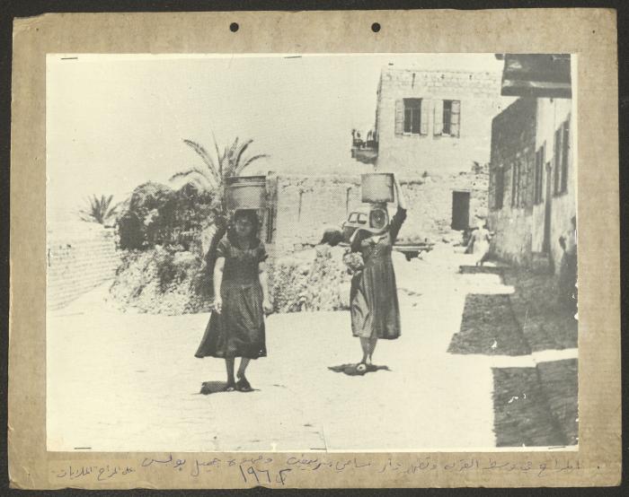 Two Women Holding Cooking Pots on Their Heads in the Centre of Kafr Yasif, 1962 