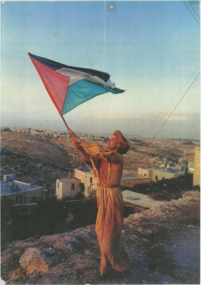 Maha el-Sakka Wearing a Traditional Beaded Thobe, and Raising the Palestinian Flag