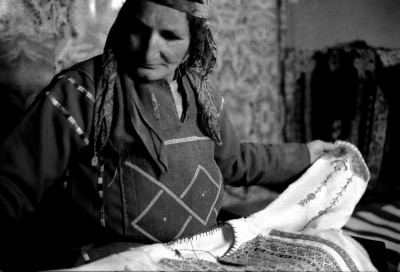 امرأة مسنّة تعاين ثوباً فلسطينياً في قرية المزرعة الشرقية، رام الله، 1988
