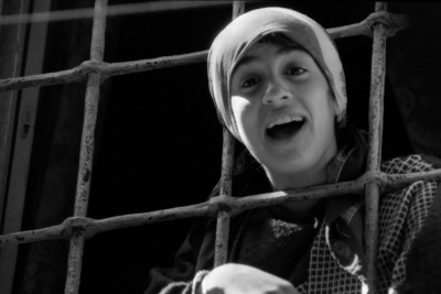 فتاة تظهر من خلف نافذة ذات قضبان حديدة خلال منع التجول في البلدة القديمة في نابلس