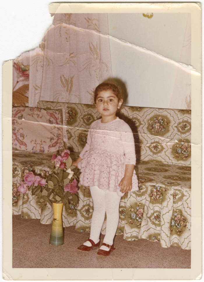A little girl standing next to a rose