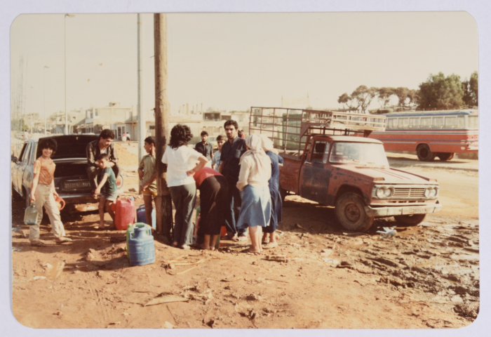 مجموعة من اللاجئين يحملون عبوات تخزين ملئت بالمياه قرب مخيم شاتيلا للاجئين