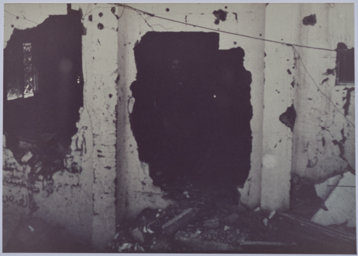 A man standing in the middle of the rubble in a bombed house. 